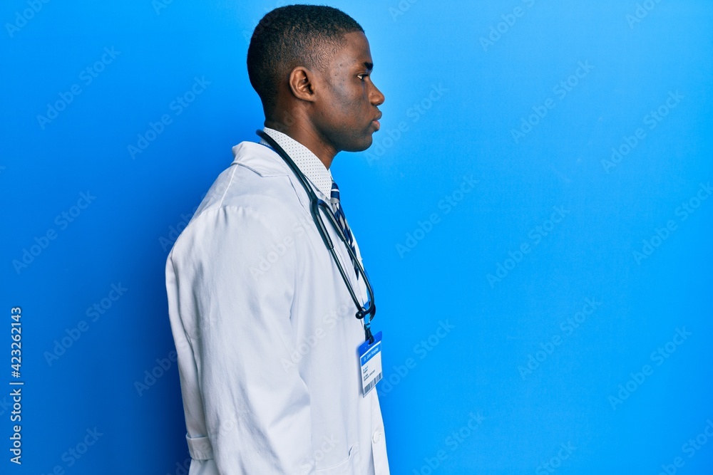 Young african american man wearing doctor uniform looking to side, relax profile pose with natural face with confident smile. Young african american man wearing doctor uniform looking to side, relax profile pose with natural face with confident smile.