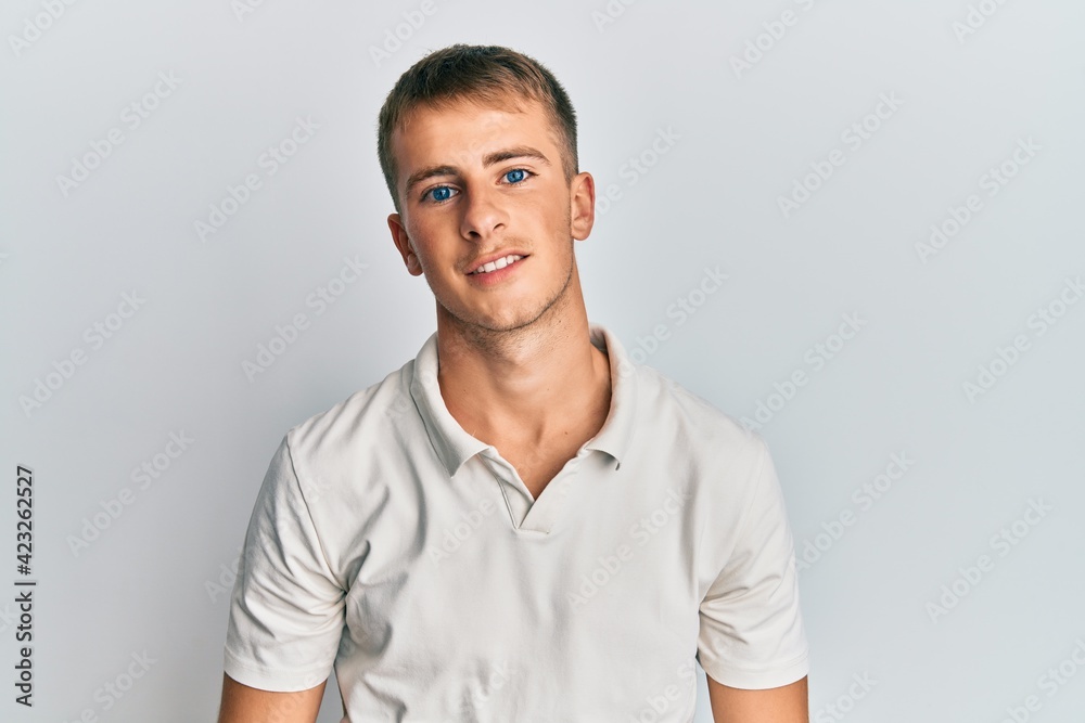 Young caucasian man wearing casual white polo with a happy and cool smile on face. lucky person. Young caucasian man wearing casual white polo with a happy and cool smile on face. lucky person.