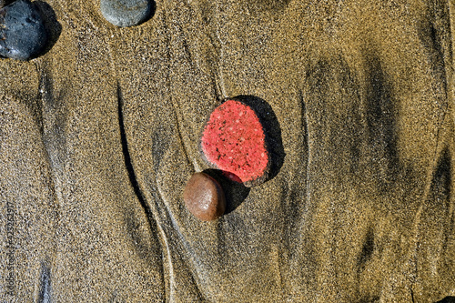 Bits of ceramics and varied stones cast away on the beach, jetsam and flotsam,  candid image of objects found on the beach, mixed basalt and silica sand in background. photo