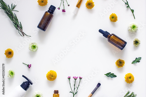 Wellness cosmetics background frame, mock up, top view, copy space. Natural cosmetic ingredients, flowers, herbs, oils, cream, bottles on a white background