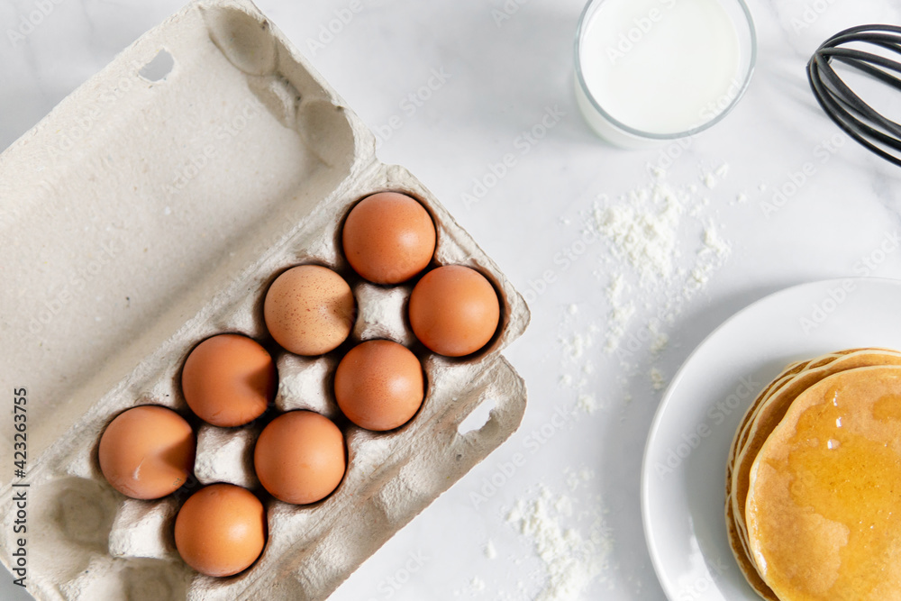 composition of small desserts for baking. eggs, muffins, flour, milk, whisk and spoon on a light background. Close-up of baked pancakes on a white plate. composition of small desserts for baking. eggs, muffins, flour, milk, whisk and spoon on a light background. Close-up of baked pancakes on a white plate.