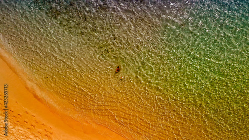 Wallpaper Mural Young girl enjoying a beautiful beach shoreline. Crystal clear ocean water, downward view from drone Torontodigital.ca