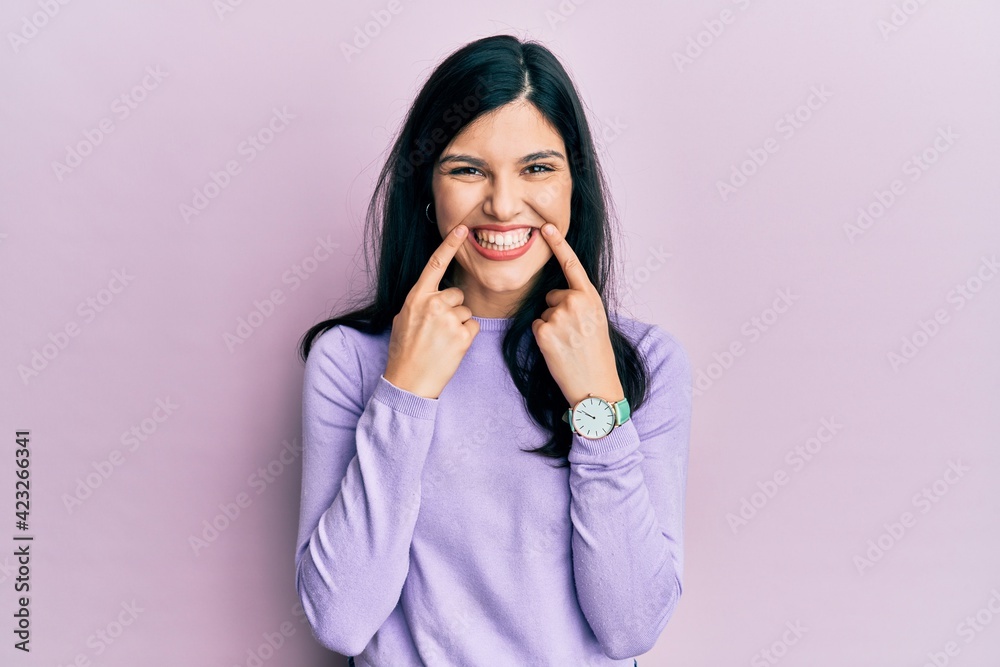 Young hispanic woman wearing casual clothes smiling with open mouth, fingers pointing and forcing cheerful smile Young hispanic woman wearing casual clothes smiling with open mouth, fingers pointing and forcing cheerful smile