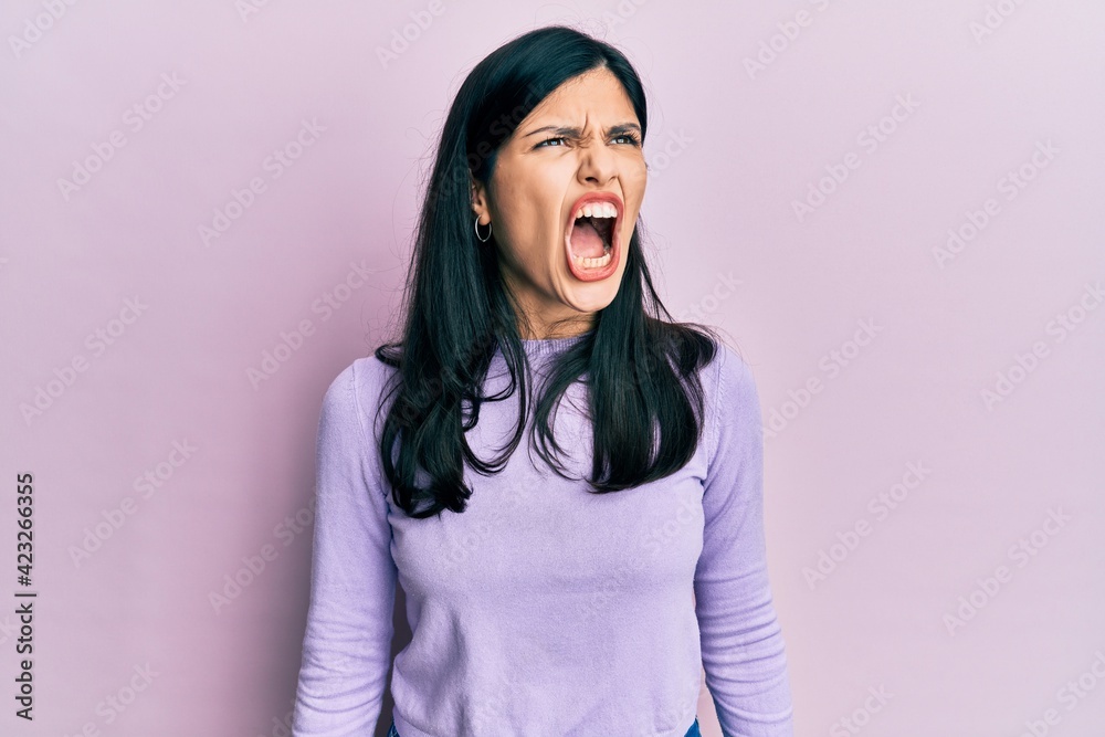 Young hispanic woman wearing casual clothes angry and mad screaming frustrated and furious, shouting with anger. rage and aggressive concept.