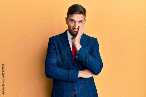 Handsome man with beard wearing business suit and tie thinking looking tired and bored with depression problems with crossed arms.