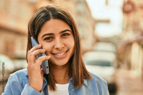 Young latin girl smiling happy talking on the smartphone at the city.