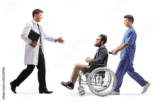 Full length profile shot of a doctor welcoming a male patient in a wheelchair