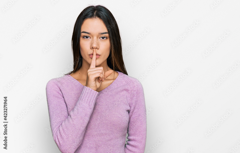 Young hispanic girl wearing casual clothes asking to be quiet with finger on lips. silence and secret concept.