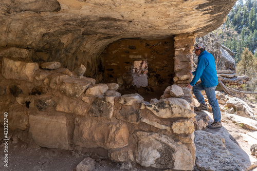 A person looking into ruined 2 room Pueblo dwellings, abandoned some 700 years ago, Island Trail, Walnut Canyon National Monument, Arizona