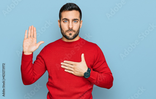 Young hispanic man wearing casual clothes swearing with hand on chest and open palm, making a loyalty promise oath