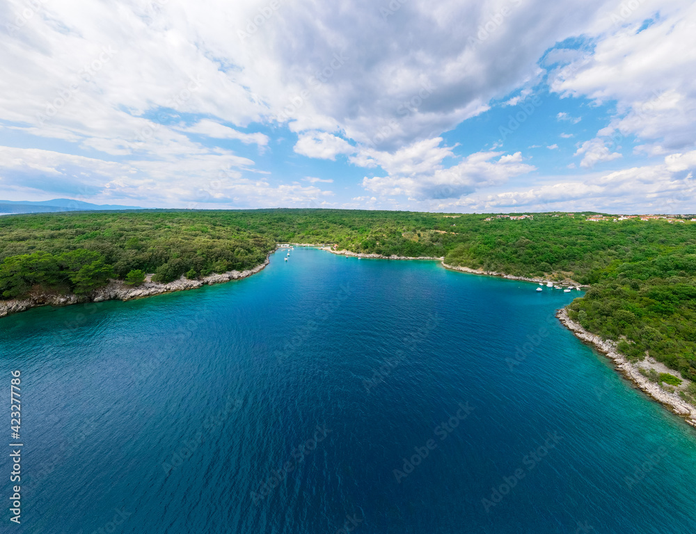 Panoramic landscape view of the blue ocean bay bordered with a coastline with green trees and with blue cloudy sky above Panoramic landscape view of the blue ocean bay bordered with a coastline with green trees and with blue cloudy sky above