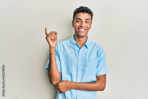 Young handsome african american man wearing casual clothes smiling happy pointing with hand and finger to the side
