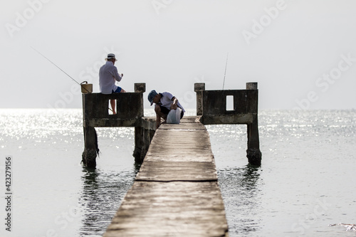 Two Unidentifiable men fishing on the pier 