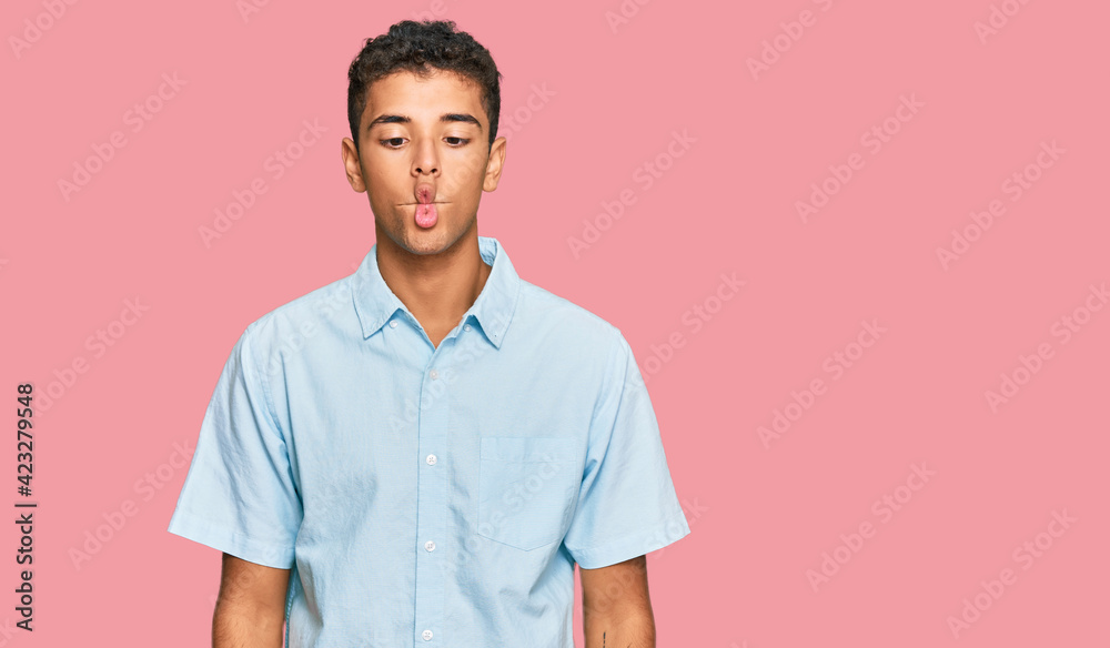 Young handsome african american man wearing casual clothes making fish face with lips, crazy and comical gesture. funny expression. Young handsome african american man wearing casual clothes making fish face with lips, crazy and comical gesture. funny expression.