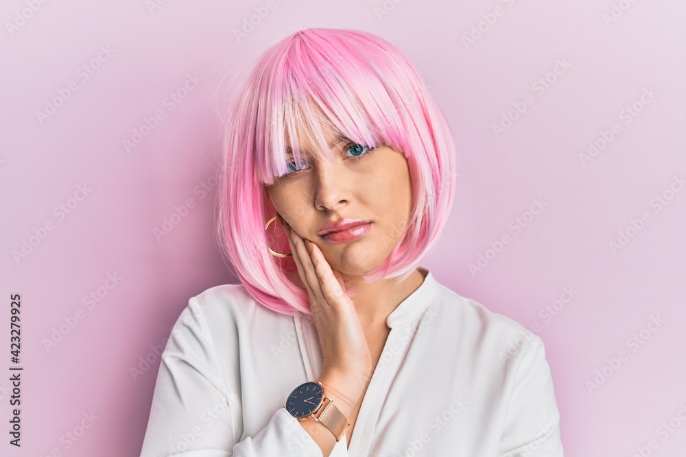 Young blonde woman wearing pink wig thinking looking tired and bored with depression problems with crossed arms. Young blonde woman wearing pink wig thinking looking tired and bored with depression problems with crossed arms.