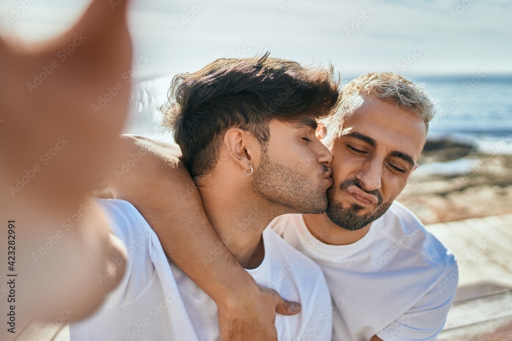 Young gay couple kissing making selfie by the camera at the beach. Young gay couple kissing making selfie by the camera at the beach.
