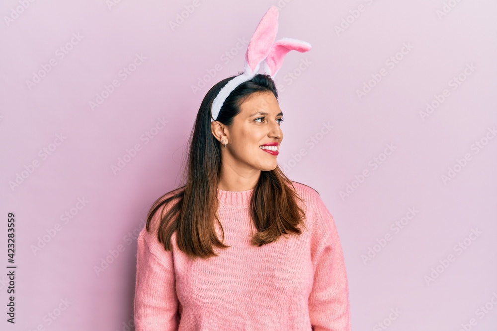 Beautiful hispanic woman wearing cute easter bunny ears looking to side, relax profile pose with natural face and confident smile.