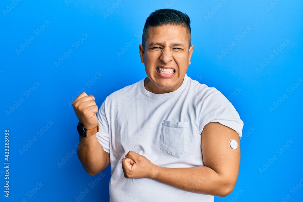 Young latin man using glucose meter button screaming proud, celebrating victory and success very excited with raised arm Young latin man using glucose meter button screaming proud, celebrating victory and success very excited with raised arm