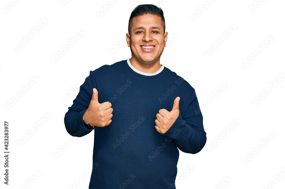 Young latin man wearing casual clothes success sign doing positive gesture with hand, thumbs up smiling and happy. cheerful expression and winner gesture. Young latin man wearing casual clothes success sign doing positive gesture with hand, thumbs up smiling and happy. cheerful expression and winner gesture.