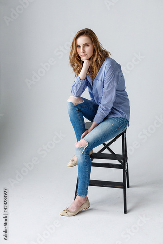 cute young caucasian pretty woman with long hair in blue shirt and ripped jeans
