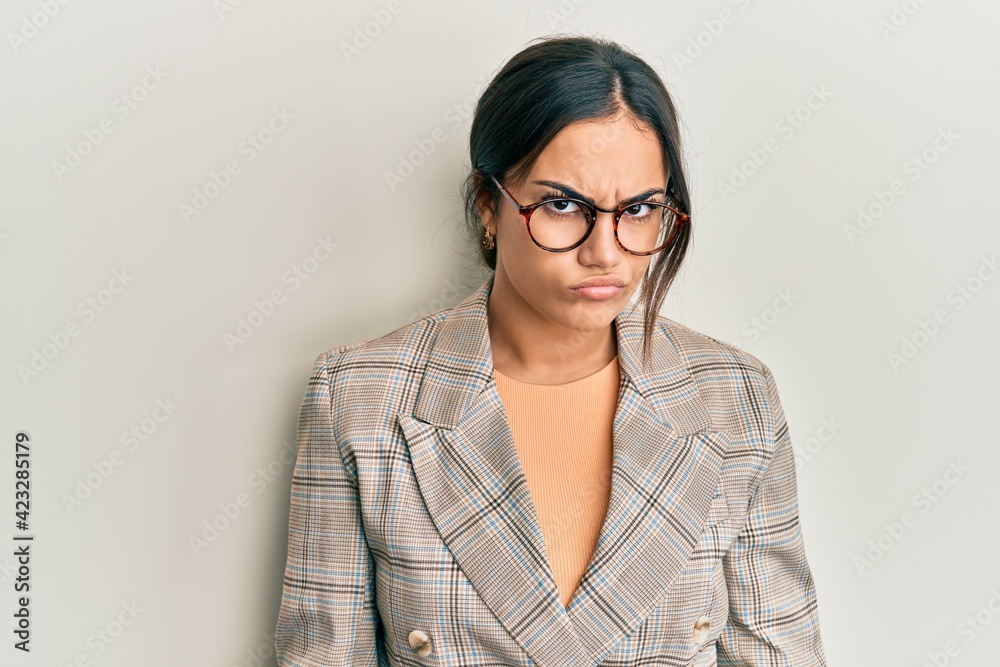 Young brunette woman wearing business jacket and glasses skeptic and nervous, frowning upset because of problem. negative person.