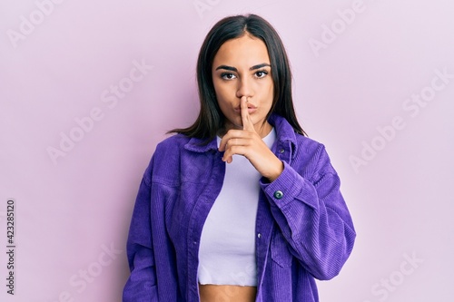Young brunette woman wearing casual clothes asking to be quiet with finger on lips. silence and secret concept.