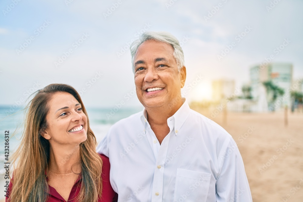 Middle age hispanic couple smiling happy walking at the beach. Middle age hispanic couple smiling happy walking at the beach.