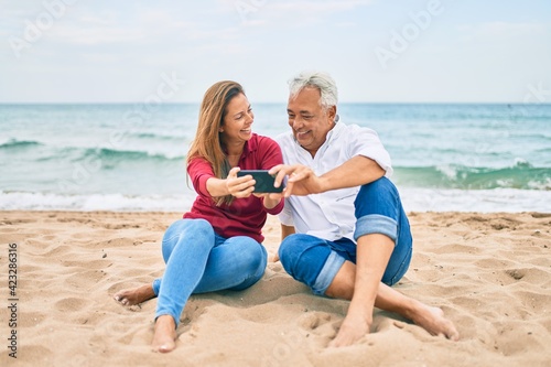 Middle age hispanic couple making selfie by the smartphone at the beach. © Krakenimages.com
