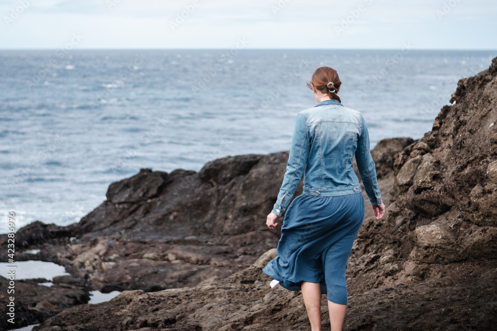 Young woman on summer vacation walking on the rocks on the coast
