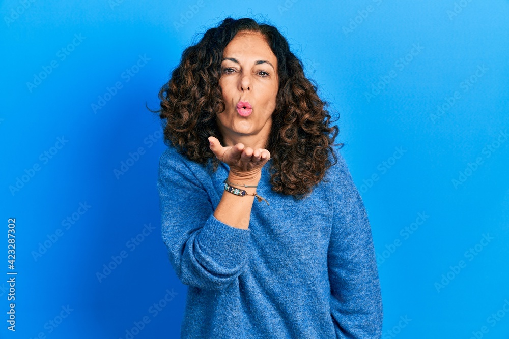 Middle age hispanic woman wearing casual clothes looking at the camera blowing a kiss with hand on air being lovely and sexy. love expression. Middle age hispanic woman wearing casual clothes looking at the camera blowing a kiss with hand on air being lovely and sexy. love expression.