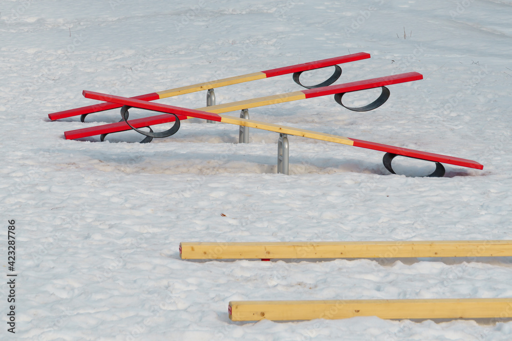 Baby seesaws outside on playground with crumbly melting spring snow