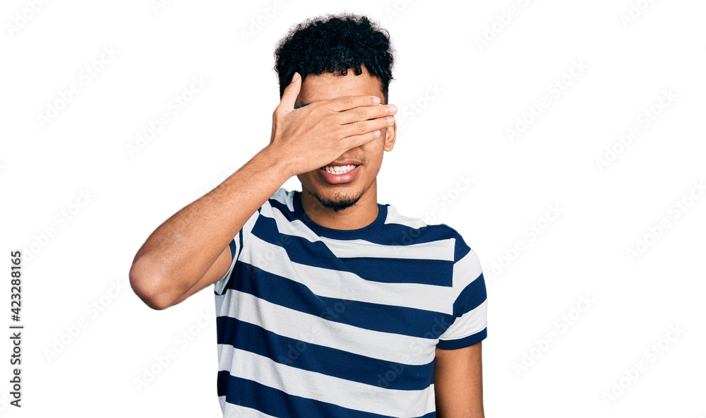 Young african american man wearing casual clothes and glasses smiling and laughing with hand on face covering eyes for surprise. blind concept. Young african american man wearing casual clothes and glasses smiling and laughing with hand on face covering eyes for surprise. blind concept.