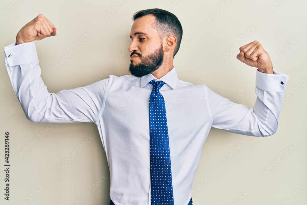 Young man with beard wearing business tie showing arms muscles smiling proud. fitness concept. Young man with beard wearing business tie showing arms muscles smiling proud. fitness concept.