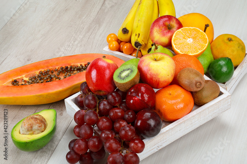 Delicious fresh fruit with grapes, tangerine, papaya, banana, avocado, orange, kiwi