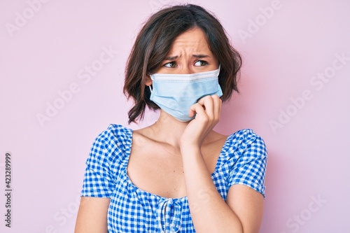Young beautiful woman wearing medical mask looking stressed and nervous with hands on mouth biting nails. anxiety problem.