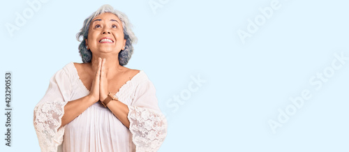 Senior woman with gray hair wearing bohemian style begging and praying with hands together with hope expression on face very emotional and worried. begging.