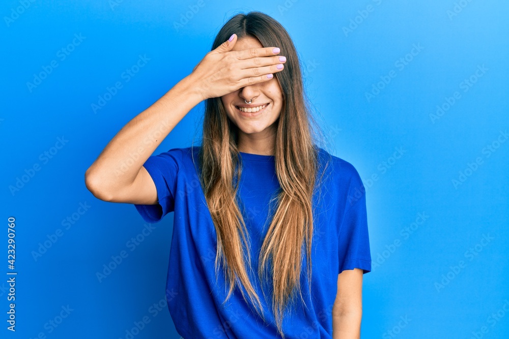 Young hispanic woman wearing casual clothes smiling and laughing with hand on face covering eyes for surprise. blind concept. Young hispanic woman wearing casual clothes smiling and laughing with hand on face covering eyes for surprise. blind concept.