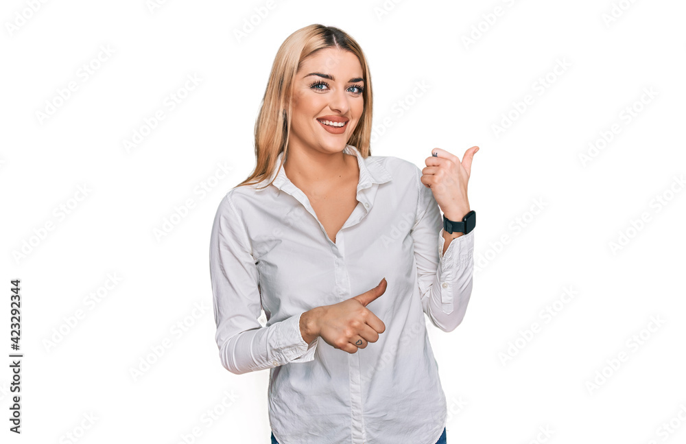 Young caucasian woman wearing casual clothes pointing to the back behind with hand and thumbs up, smiling confident Young caucasian woman wearing casual clothes pointing to the back behind with hand and thumbs up, smiling confident