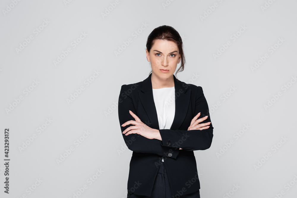 Brunette businesswoman with crossed arms looking at camera isolated on grey Brunette businesswoman with crossed arms looking at camera isolated on grey