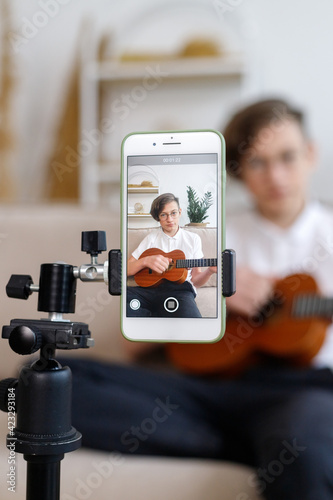boy tunes guitar, before playing guitar, home teaching music, handsome boy tunes the guitar, before playing the guitar, home teaching music. student tunes a musical instrument, online lesson ukulele