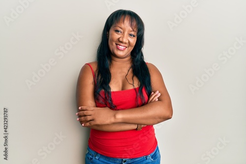 Middle age african american woman wearing casual style with sleeveless shirt happy face smiling with crossed arms looking at the camera. positive person.