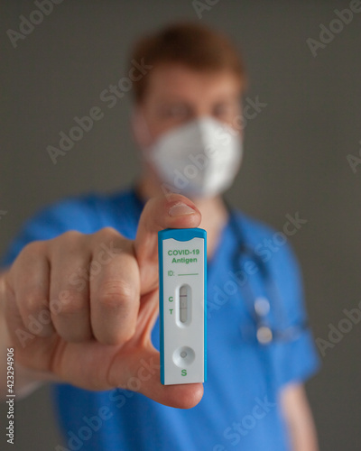 the doctor with stethoscope and mask holding positive antigen test Covid-19