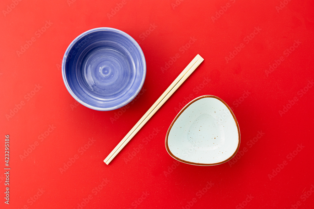 Empty food bowls with chopsticks on red background Empty food bowls with chopsticks on red background