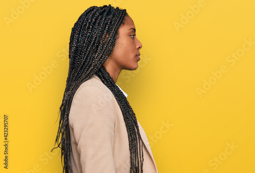 African american woman wearing business jacket looking to side, relax profile pose with natural face and confident smile.
