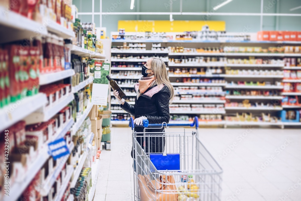 Woman in a face mask, shopping at the supermarket, shopping during the COVID-19 pandemic.