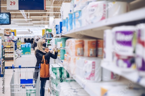 Woman with face mask and gloves on shopping at supermarket.