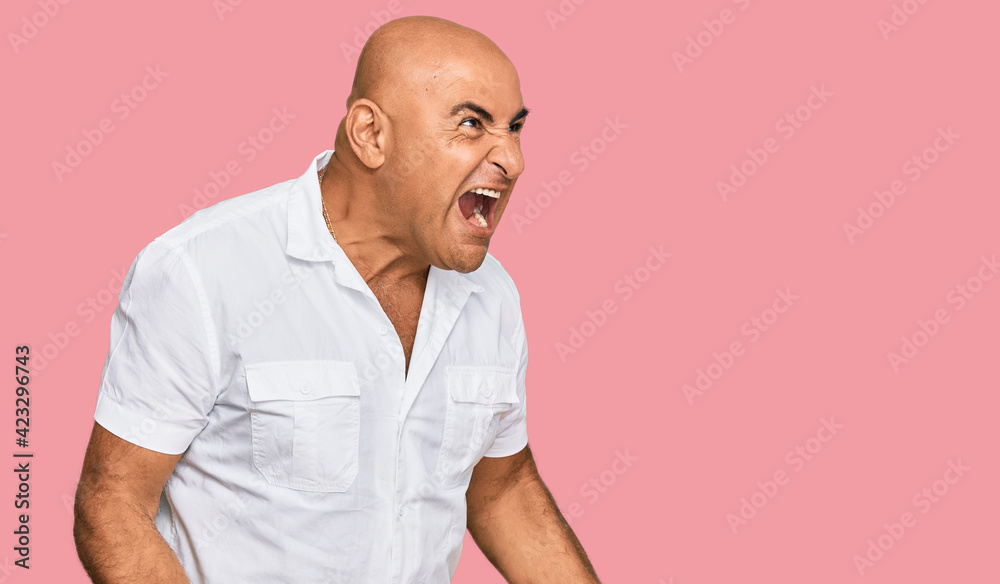 Mature middle east man with mustache wearing casual white shirt angry and mad screaming frustrated and furious, shouting with anger. rage and aggressive concept. Mature middle east man with mustache wearing casual white shirt angry and mad screaming frustrated and furious, shouting with anger. rage and aggressive concept.