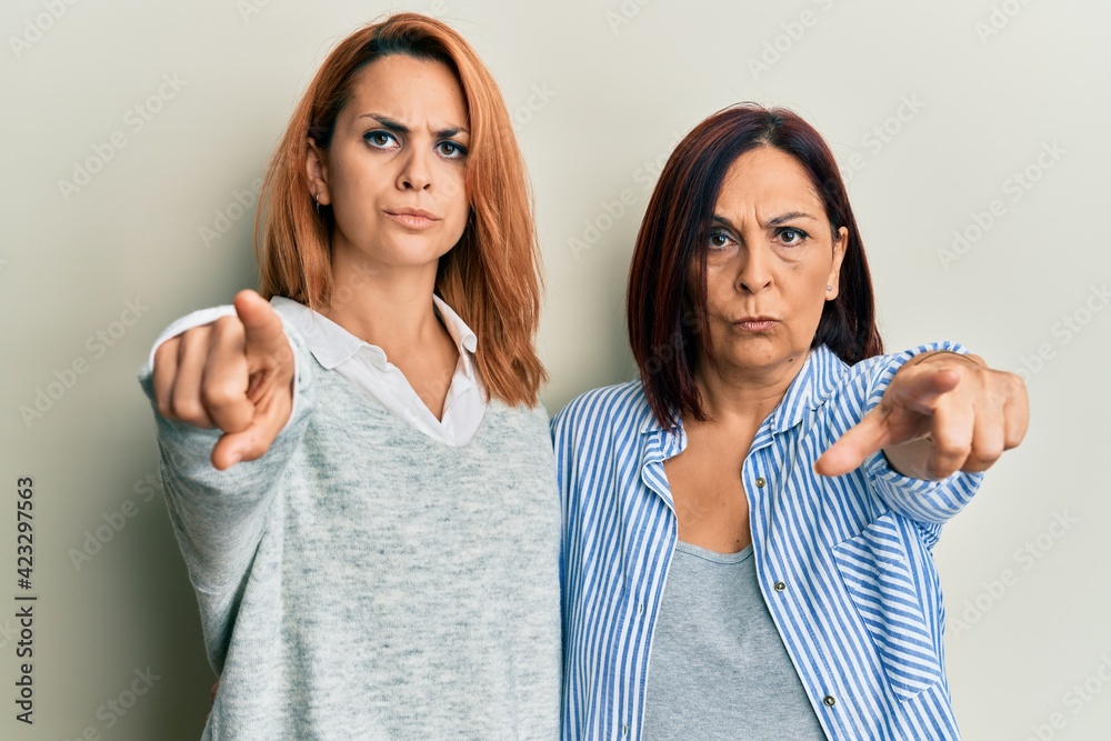 Latin mother and daughter wearing casual clothes pointing with finger to the camera and to you, confident gesture looking serious Latin mother and daughter wearing casual clothes pointing with finger to the camera and to you, confident gesture looking serious