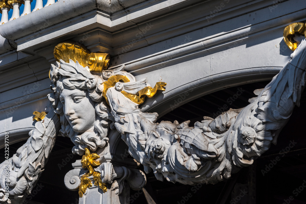 Fototapeta premium A sculpture of a women's face adorns the Beau Art Pont Alexander III bridge in Paris France.