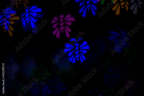 Defocused image of multicolored bees on an abstract background. Dark background, blur bokeh.